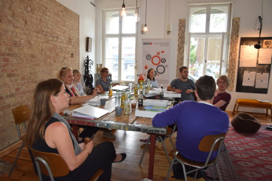 Ein Dutzend Menschen sitzen um einen Tisch herum.