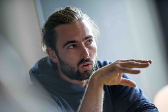 Ein junger Mann mit Bart erklärt etwas.