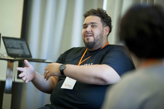 Ein junger Mann erklärt etwas vor einer kleinen Runde von Zuhörern. kleine