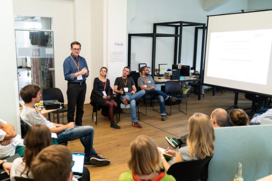 Ein Mann steht in einem Stuhlkreis und spricht.