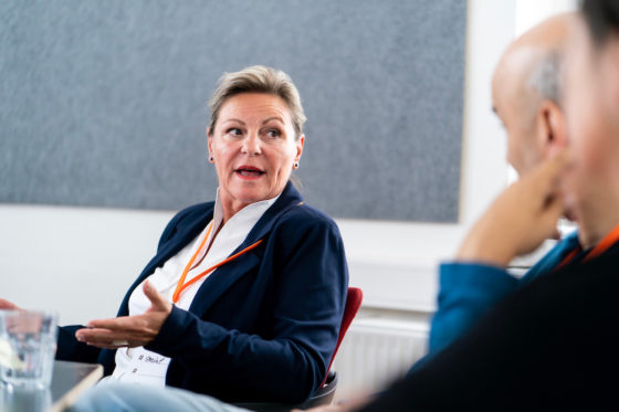 Eine Frau spricht zu einer Gruppe Menschen.