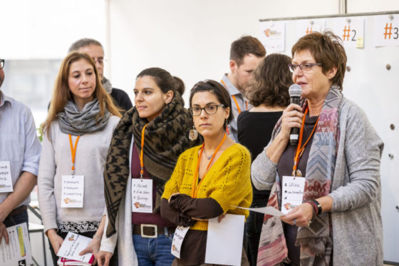 Eine Frau spricht in ein Mikrofon, mehrere Frauen stehen neben ihr.