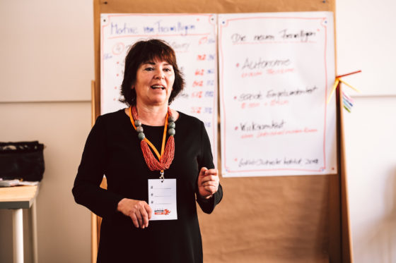 Eine Frau steht vor einer Metaplanwand und spricht.