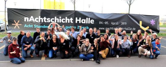 30 Menschen sitzen vor einem Banner mit dem Schriftzug 