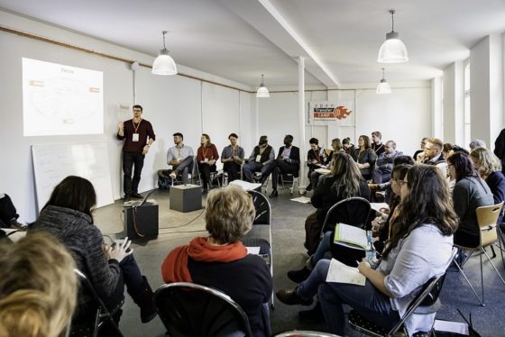Ein Mann referiert vor zwei Dutzend Menschen