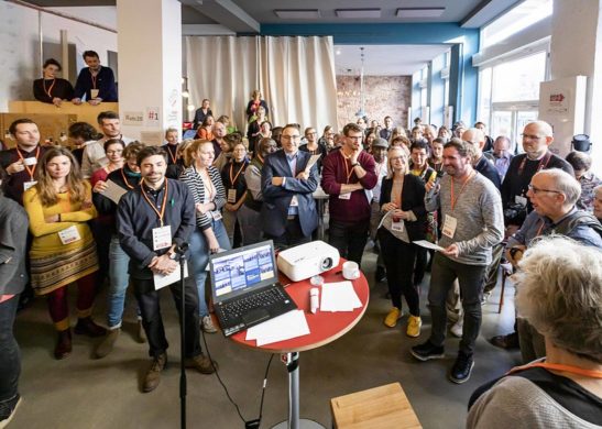 Ein Mann mit Mikro steht in einer Menschentraube.