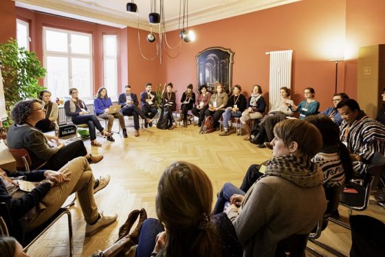 Rund 20 Menschen sitzen in einem Stuhlkreis.